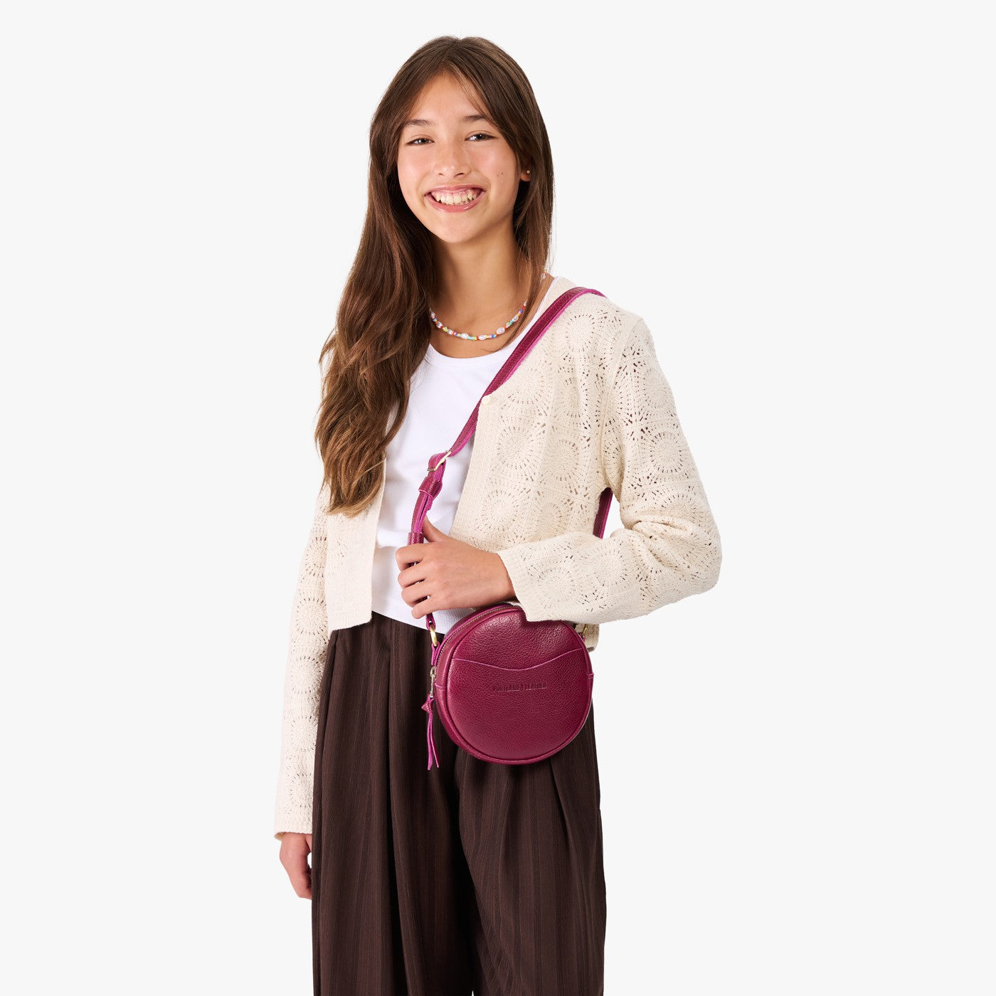 Orchid | Model wearing a circle shaped crossbody bag with top zipper and gold accents