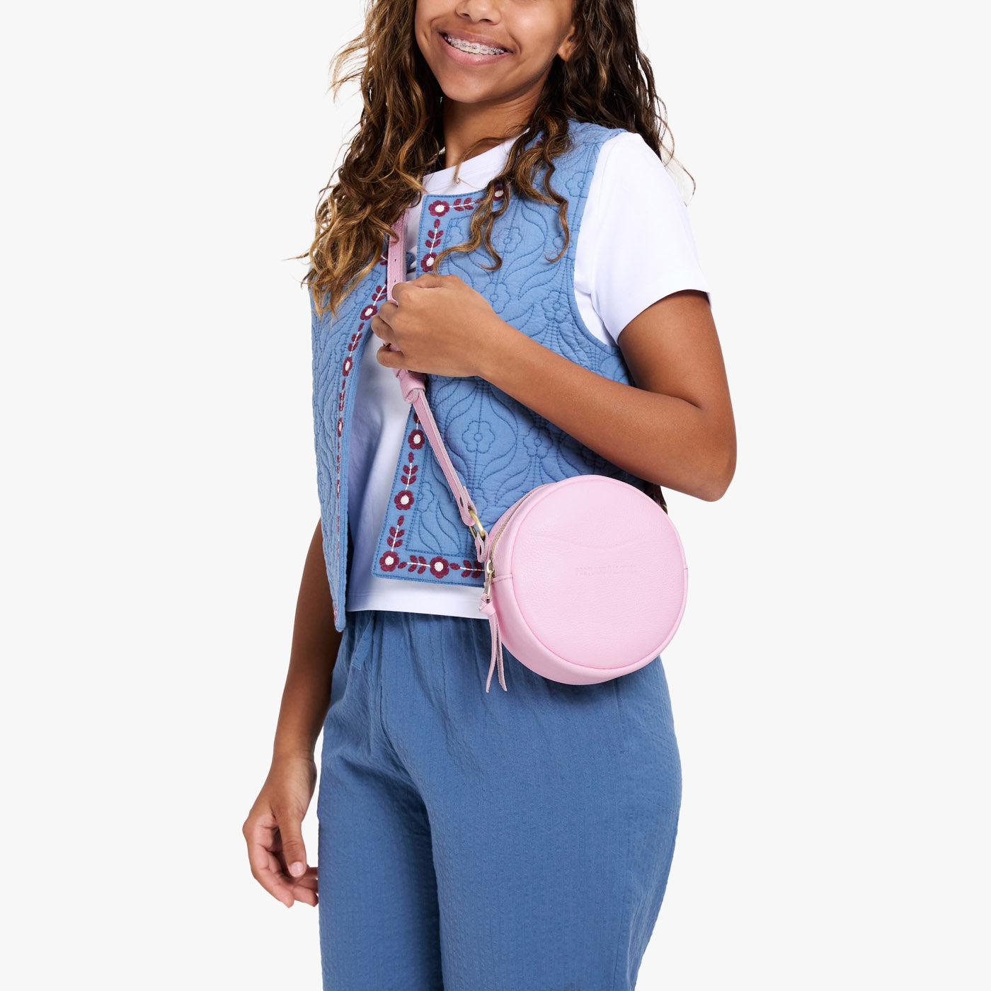 Pinkaboo | Model wearing a circle shaped crossbody bag with top zipper and gold accents
