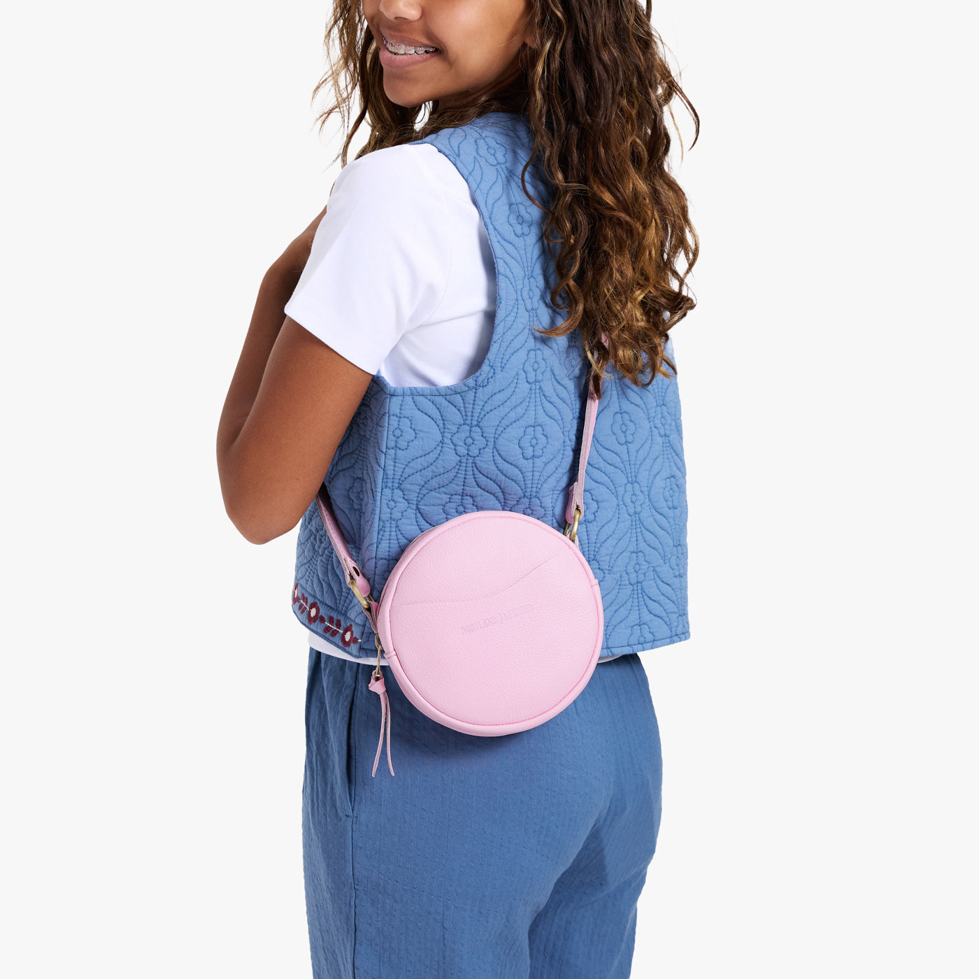 Pinkaboo | Model wearing a circle shaped crossbody bag with top zipper and gold accents