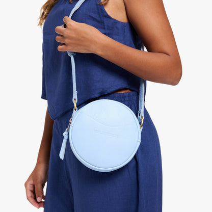 Skyway | Model wearing a circle shaped crossbody bag with top zipper and gold accents