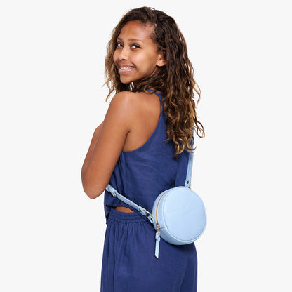 Skyway | Model wearing a circle shaped crossbody bag with top zipper and gold accents