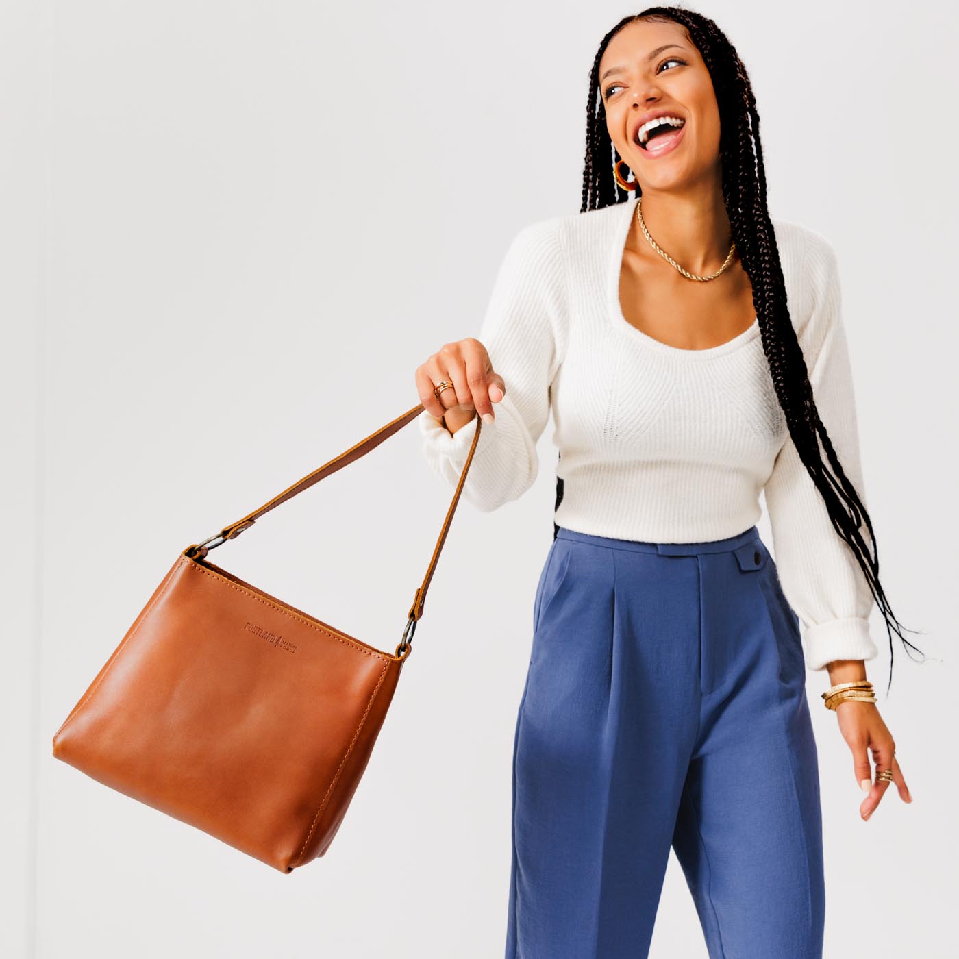Honey*Classic | Model holding leather triangular shoulder bag with zipper top closure and wide shoulder strap
