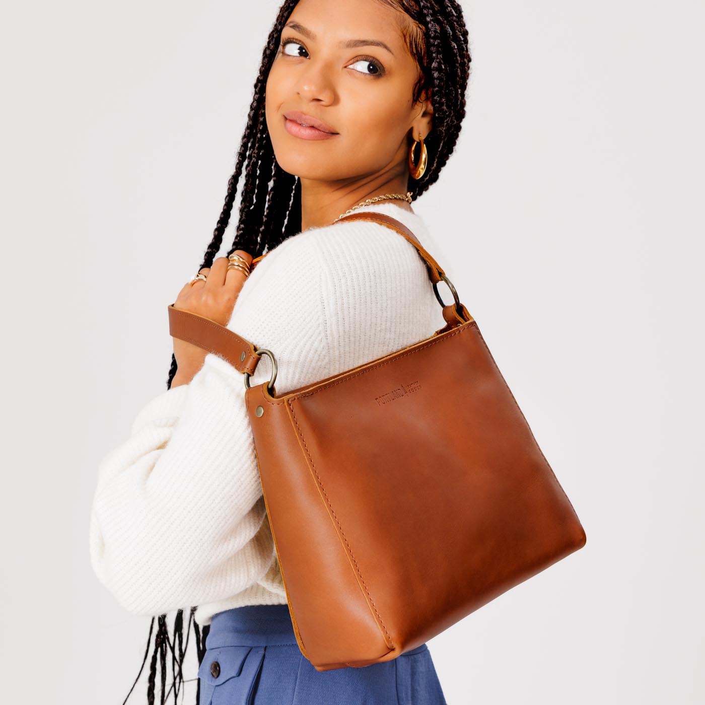 Honey*Classic | Model carrying leather triangular shoulder bag with zipper top closure and wide shoulder strap