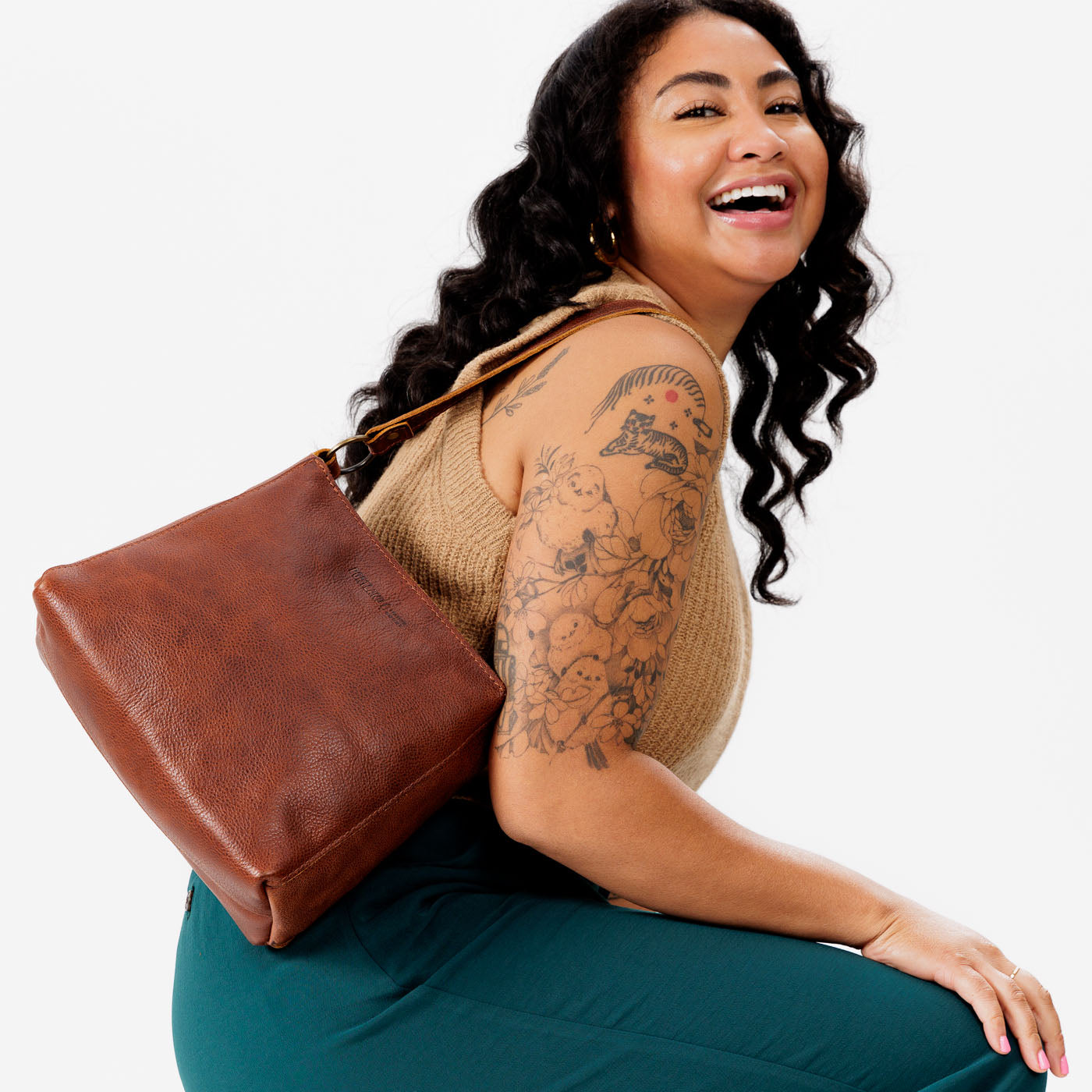 Nutmeg*Classic | Model carrying leather triangular shoulder bag with zipper top closure and wide shoulder strap