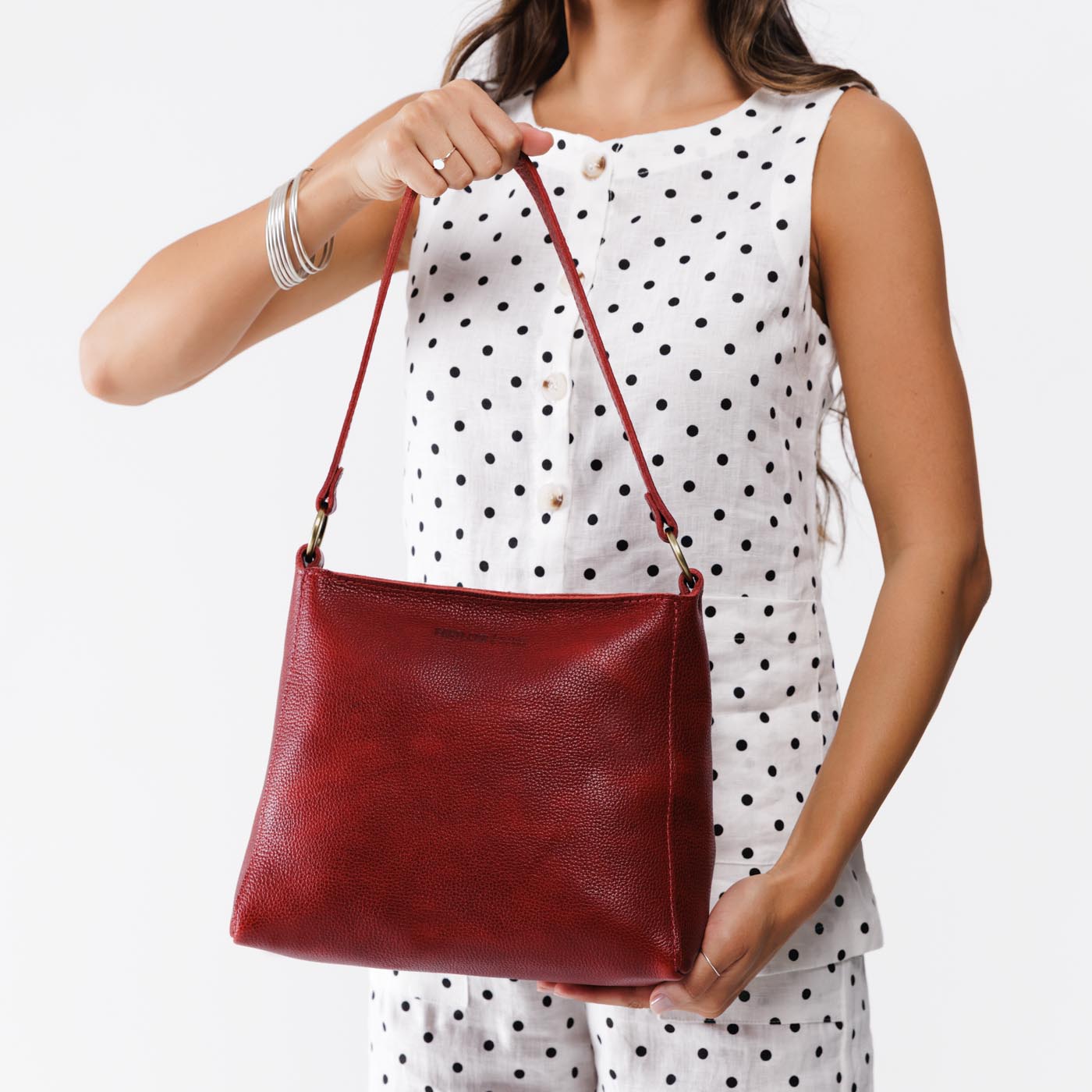 Chili Red*Small | Model holding triangular shoulder bag with antiqued brass finished hardware
