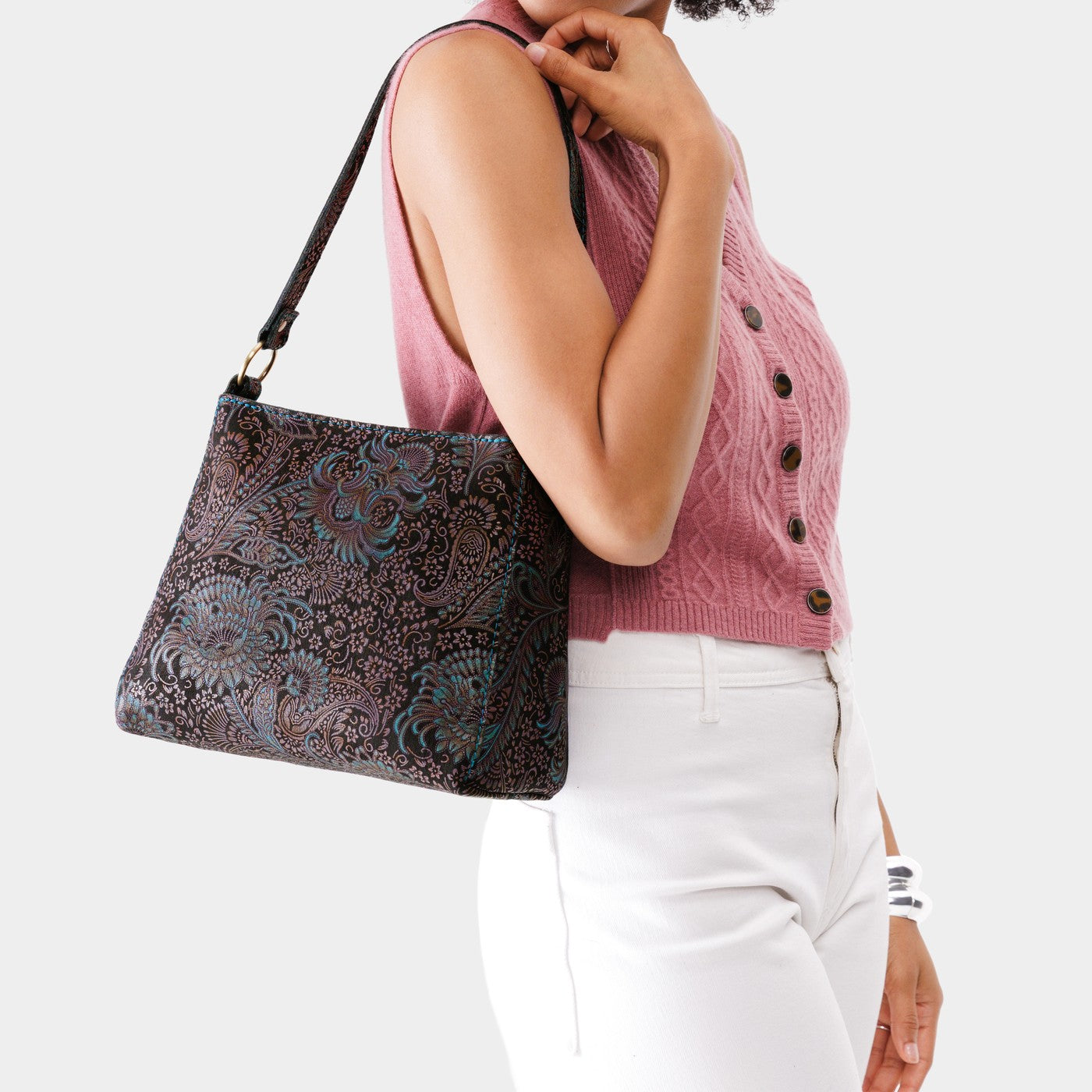 Masquerade*Small | Model carrying leather triangular shoulder bag with zipper top closure and wide shoulder strap