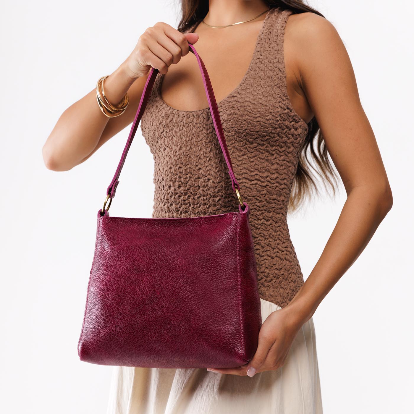 Orchid*Small | Model carrying leather triangular shoulder bag with zipper top closure and wide shoulder strap