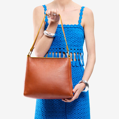 Sienna*Small | Model holding triangular shoulder bag with antiqued brass finished hardware