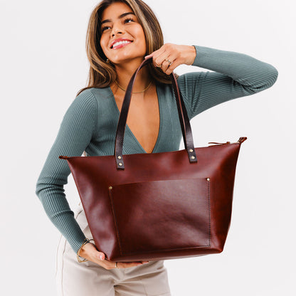 Cognac*Zipper | Model holding large zipper leather tote bag with sturdy bridle handles and front pocket